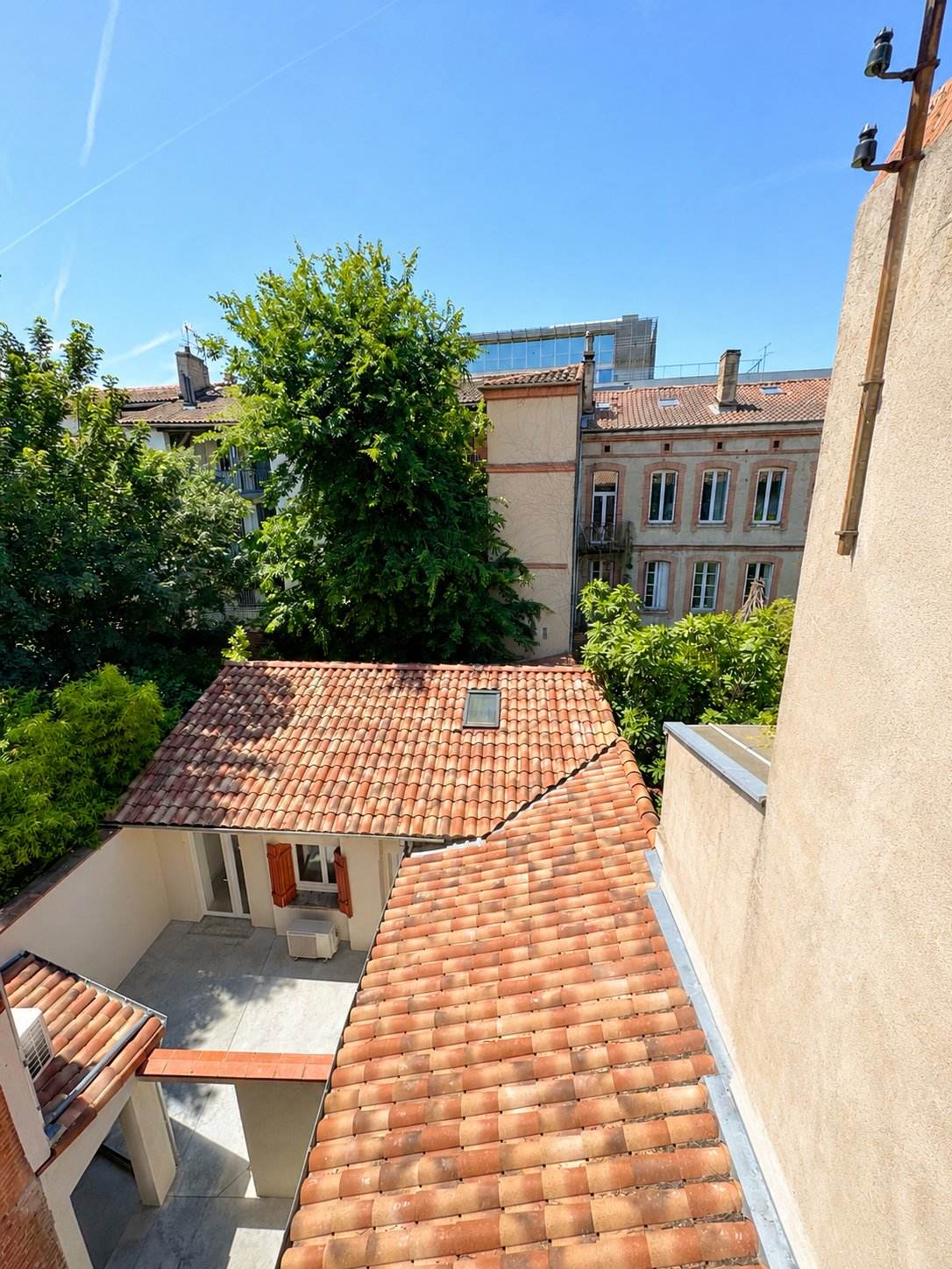 Vue dégagée sur les toits de tuiles et les façades toulousaines depuis l'immeuble